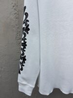 Maglietta bianca a manica lunga con decoro floreale nero, stile elegante e casual.