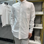 Camicia bianca a maniche lunghe, stile casual elegante, donna in negozio moda moderna.