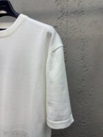 Maglietta bianca casual con polsini arrotolati e linea semplice, perfetta per look moderne e confortevoli.
