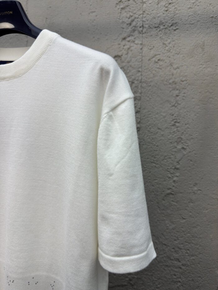 Maglietta bianca casual con polsini arrotolati e linea semplice, perfetta per look moderne e confortevoli.