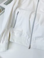 Giacca bianca minimalista con zip frontale e polsini elasticizzati, perfetta per stile e comfort.