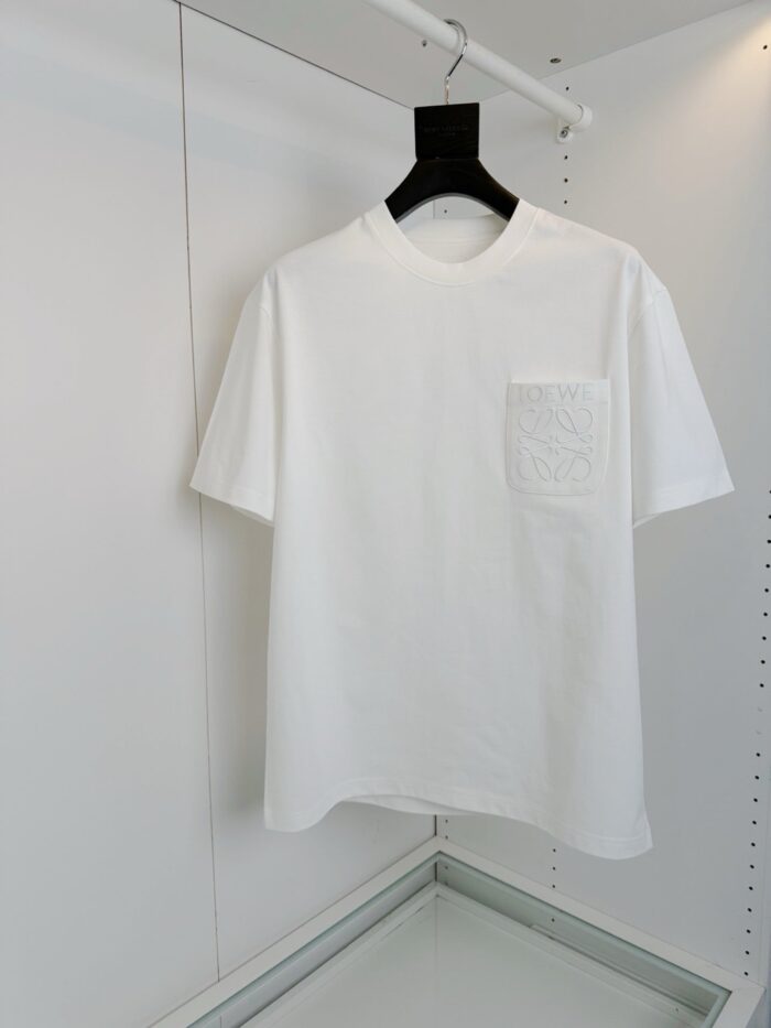 Maglietta bianca semplice con tasca decorativa, ideale per outfit casual e stile minimalista.