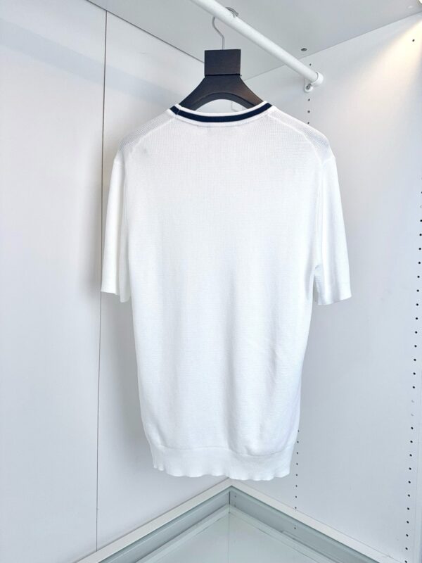 Camicia bianca minimalista con dettaglio blu navy sul collo, stile elegante e versatile.