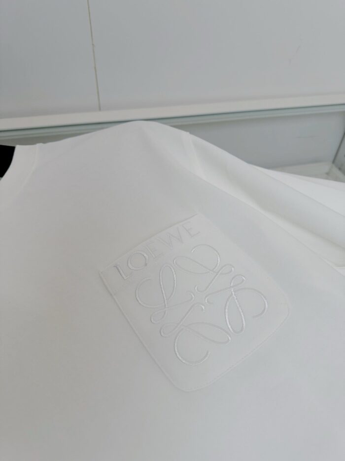 Maglietta bianca minimalista con logo embossato in dettaglio, tessuto morbido e stile elegante.