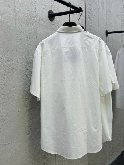 Camicia bianca minimalista con colletto classico, maniche corte, elegante e versatile.