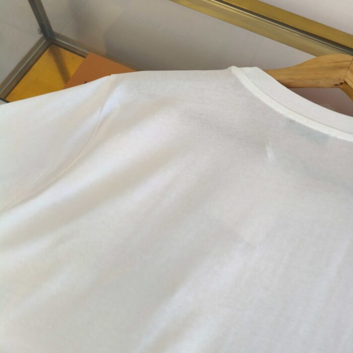 Maglietta bianca minimalista con collo classico su legno, stile semplice ed elegante.