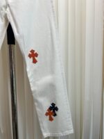 Pantaloni bianchi con cross colorati, stile moderno, casual e trendy, su gruccia in ambiente elegante.