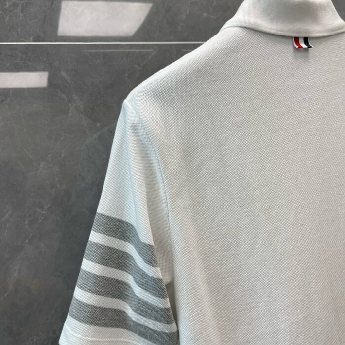 Maglietta polo bianca con dettagli grigi, stile elegante e sportivo, ideale per look casual e sofisticati.