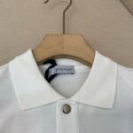 Polo Moncler bianca elegante con colletto strutturato e bottone metallico lucido.