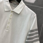 Maglietta polo bianca con dettagli a righe grigie, stile classico e design moderno elegante.