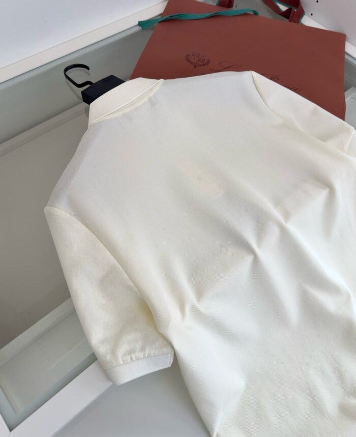 Camicia polo bianca con borsa in pelle elegante, stile casual sofisticato e di qualità.