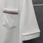 Maglietta polo bianca con taschino colorato, maniche rollate e tessuto pique elegante.