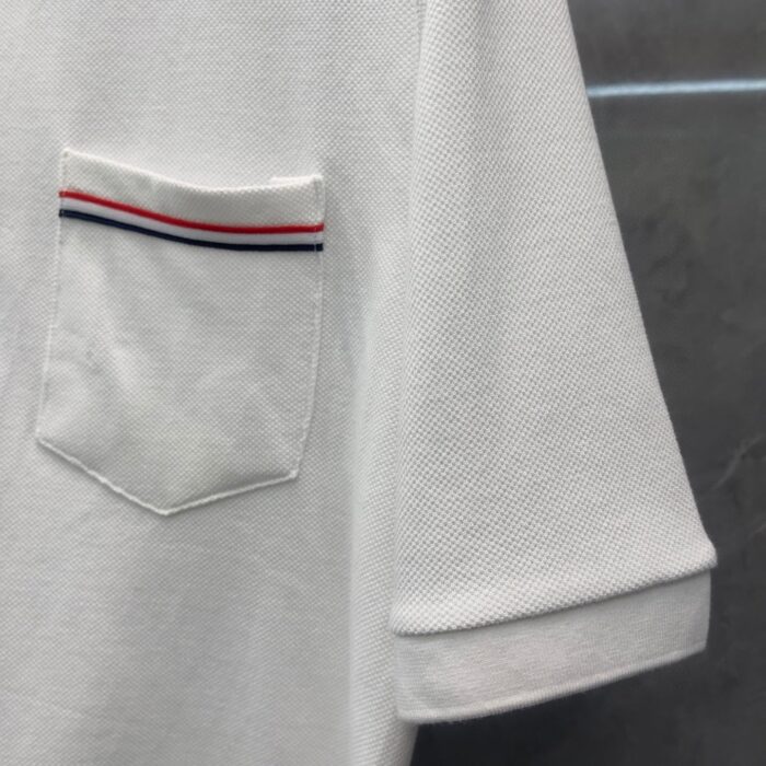 Maglietta polo bianca con taschino colorato, maniche rollate e tessuto pique elegante.