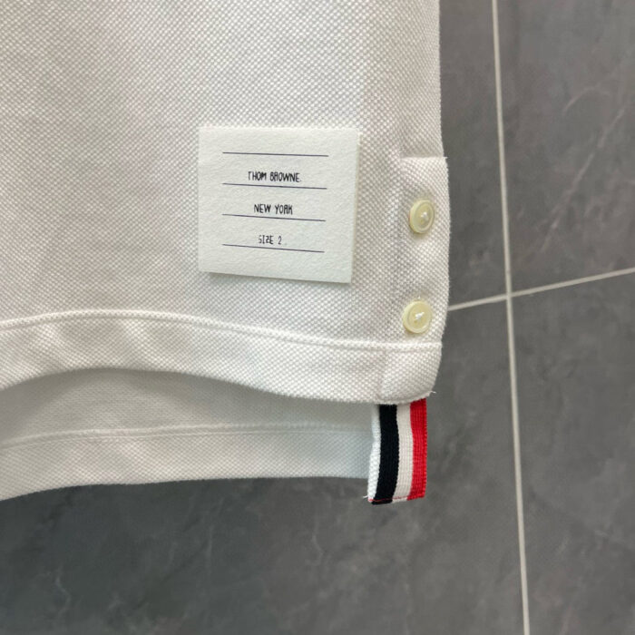 Maglietta polo bianca con etichetta TOP MAN e dettagli colorati, stile casual e sportivo.