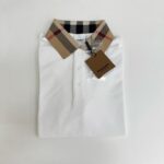 Maglietta polo bianca con colletto check beige e nero, stile classico e versatile.