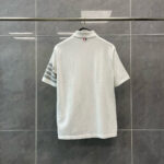 Maglietta polo bianca con strisce laterali e logo, stile sportivo e moderno.