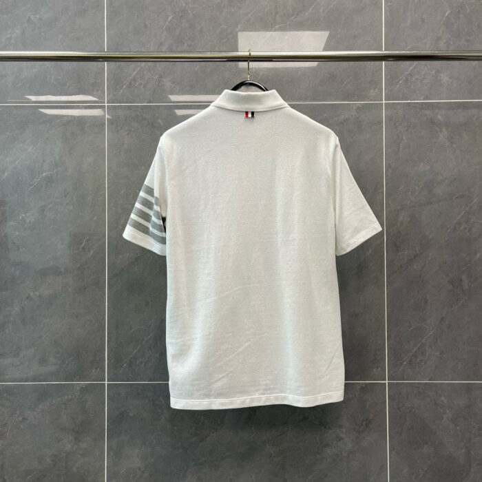 Maglietta polo bianca con strisce laterali e logo, stile sportivo e moderno.