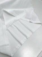 Tessuto bianco liscio con pieghe eleganti, perfetto per abbigliamento e decorazioni raffinate.