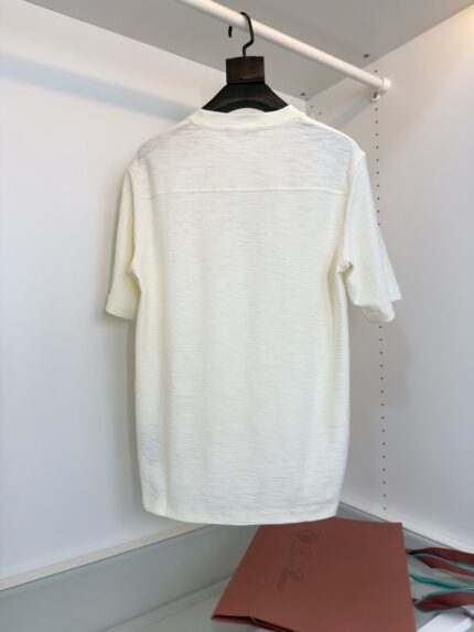 Maglietta bianca minimalista su gancio, stile casual e moderno in ambiente organizzato.