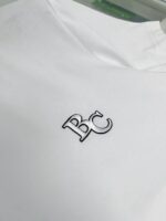 Maglietta bianca con logo ricamato nero, stile minimalista e di alta qualità.