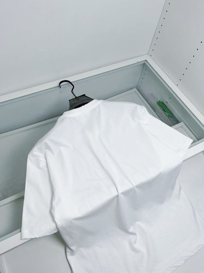 Maglietta bianca elegante in vetrina di vetro con accessorio verde, stile minimalista e moderno.
