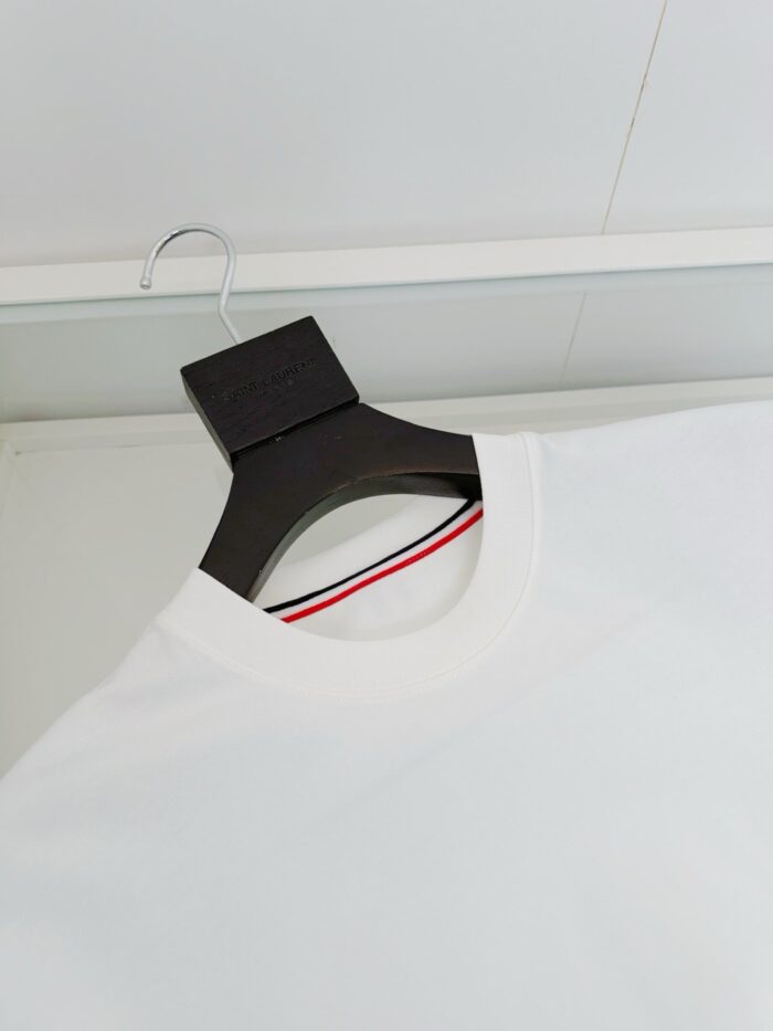 Maglietta bianca casual con colletto a strisce e appendino nero, stile minimalista e moderno.
