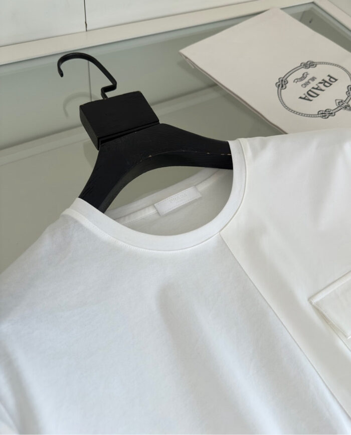 Maglietta bianca moderna con dettaglio a contrasto su appendiabiti nero, stile minimalista e contemporaneo.
