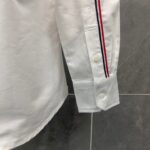 Camicia bianca elegante con polsino a strisce blu e rosso, dettagli moderno e raffinato.