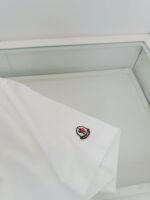 Camicia bianca elegante con logo ricamato, esposta in vetrina minimalista e luminosa.