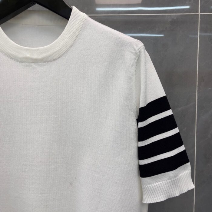 Maglietta bianca con dettagli a righe nere sulle maniche, stile casual e sporty.