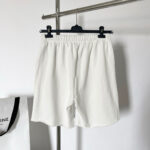 Shorts bianchi casual con elastico, stile minimalista su gruccia elegante.