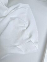 Tessuto bianco morbido, elegante, con dettagli delicati e texture raffinata in close-up.