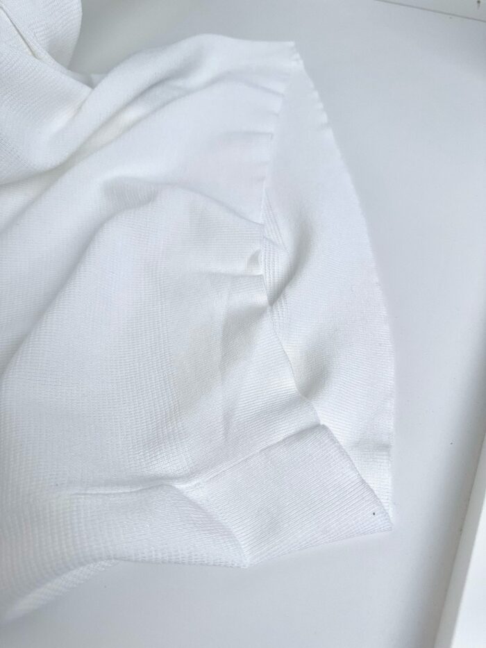 Tessuto bianco morbido, elegante, con dettagli delicati e texture raffinata in close-up.