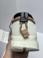 Sneaker bianca con cinturino nero, dettagli moderni e supporto pratico, vista da dietro.