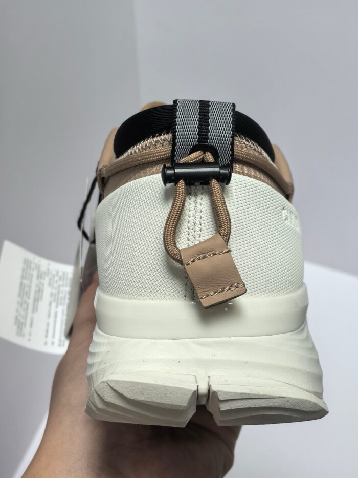 Sneaker bianca con cinturino nero, dettagli moderni e supporto pratico, vista da dietro.
