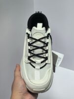 Sneaker bianco moderno con lacci neri, logo circolare e tallone nero, stile sportivo e urbano.