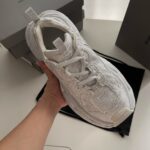 Sneaker bianca leggera e traspirante, in mano, stile moderno e dettagli premium.