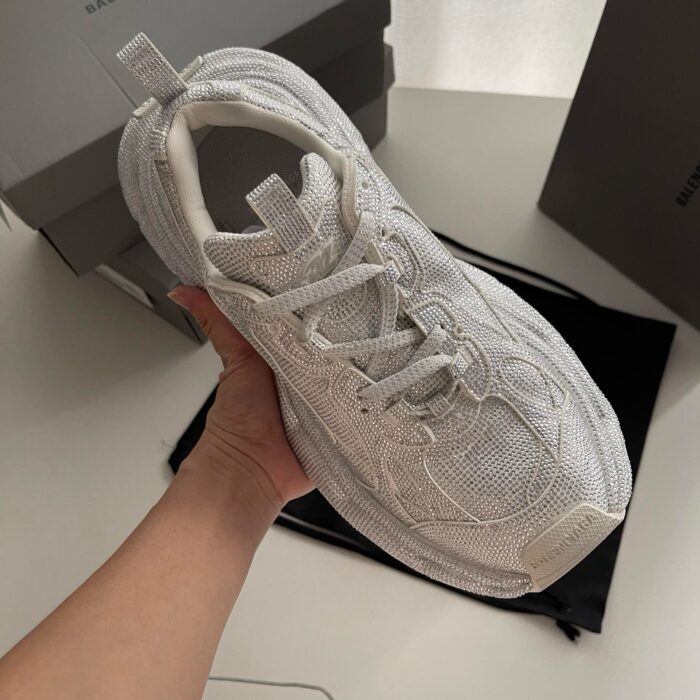Sneaker bianca leggera e traspirante, in mano, stile moderno e dettagli premium.