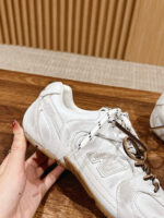 Sneaker New Balance bianca, minimalista, con lacci marroni e dettagli dorati, stile e comfort.