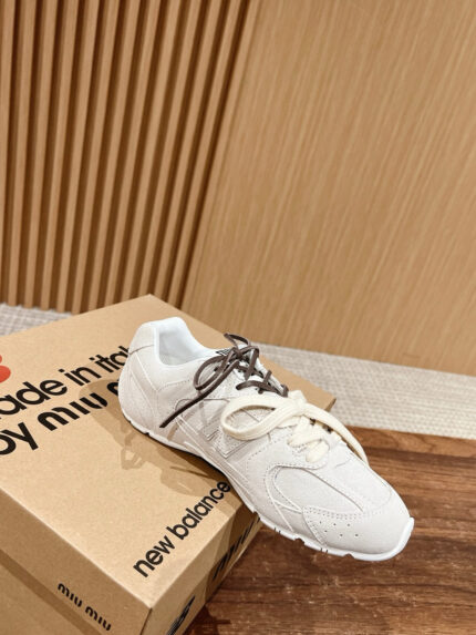 Sneaker bianca con lacci marroni su scatola Miu Miu e New Balance, stile moderno e di alta qualità.