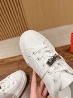 Sneaker bianca moderna con cinturino in metallo, stile casual e design elegante.