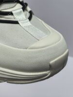 Sneaker bianca moderna con lacci riflettenti, punta in gomma e design elegante per ogni occasione.