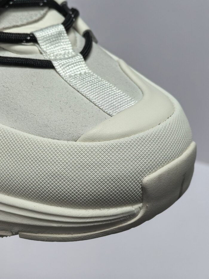 Sneaker bianca moderna con lacci riflettenti, punta in gomma e design elegante per ogni occasione.