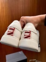 Scarpe sportive bianche con logo rosso TN, stile moderno e dettagli textured.