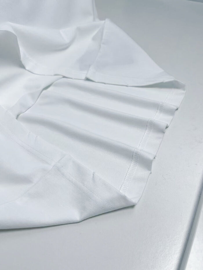 Tessuto bianco leggero, morbido, riflette la luce, con pieghe delicate e finiture eleganti.