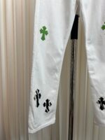 Pantaloni bianchi con croci nere e verdi, stile streetwear moderno e di tendenza.