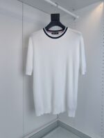 Maglione bianco a manica corta con colletto a righe navy e rosso, stile casual ed elegante.