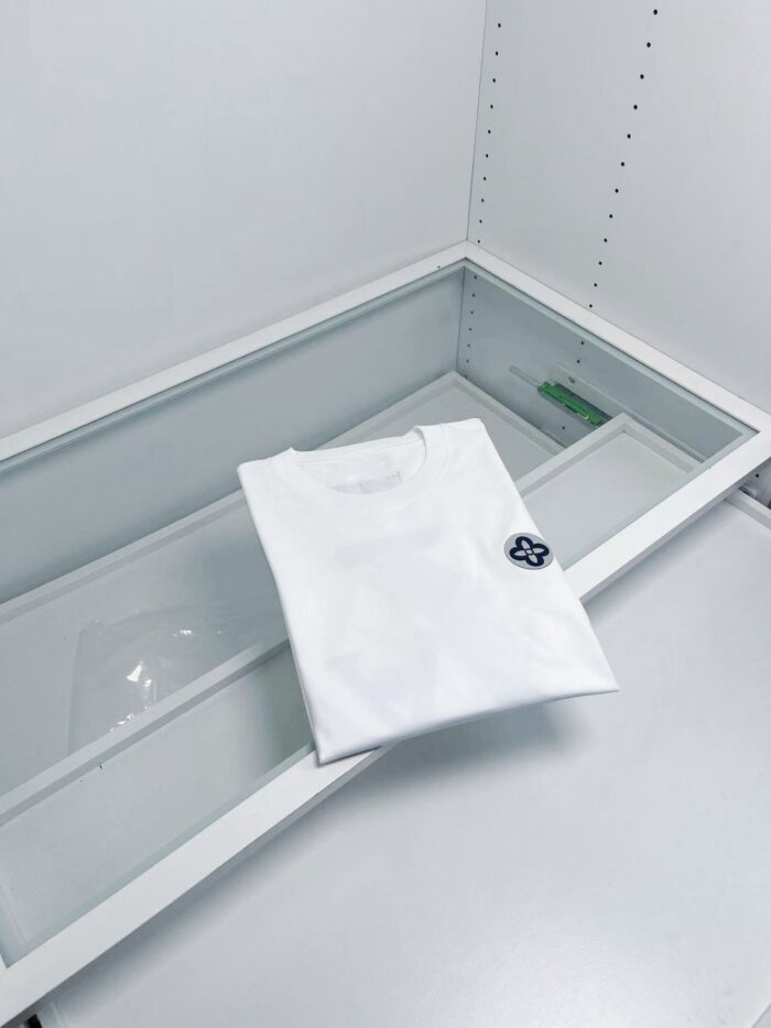 Maglietta bianca minimalista in esposizione elegante con logo discreto e stile contemporaneo.