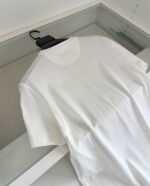 Maglietta bianca semplice su appendiabiti nero in ambiente minimalista e ordinato.