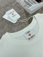 Maglietta bianca Casa Blanca con etichette eleganti e logo rosso, stile minimalista e moderno.